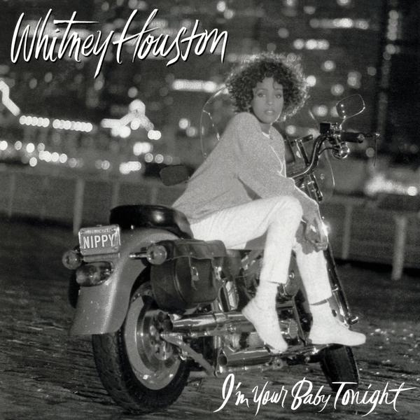 Whitney Houston motoron, fehér nadrágban, városi háttérrel. Album borítója.