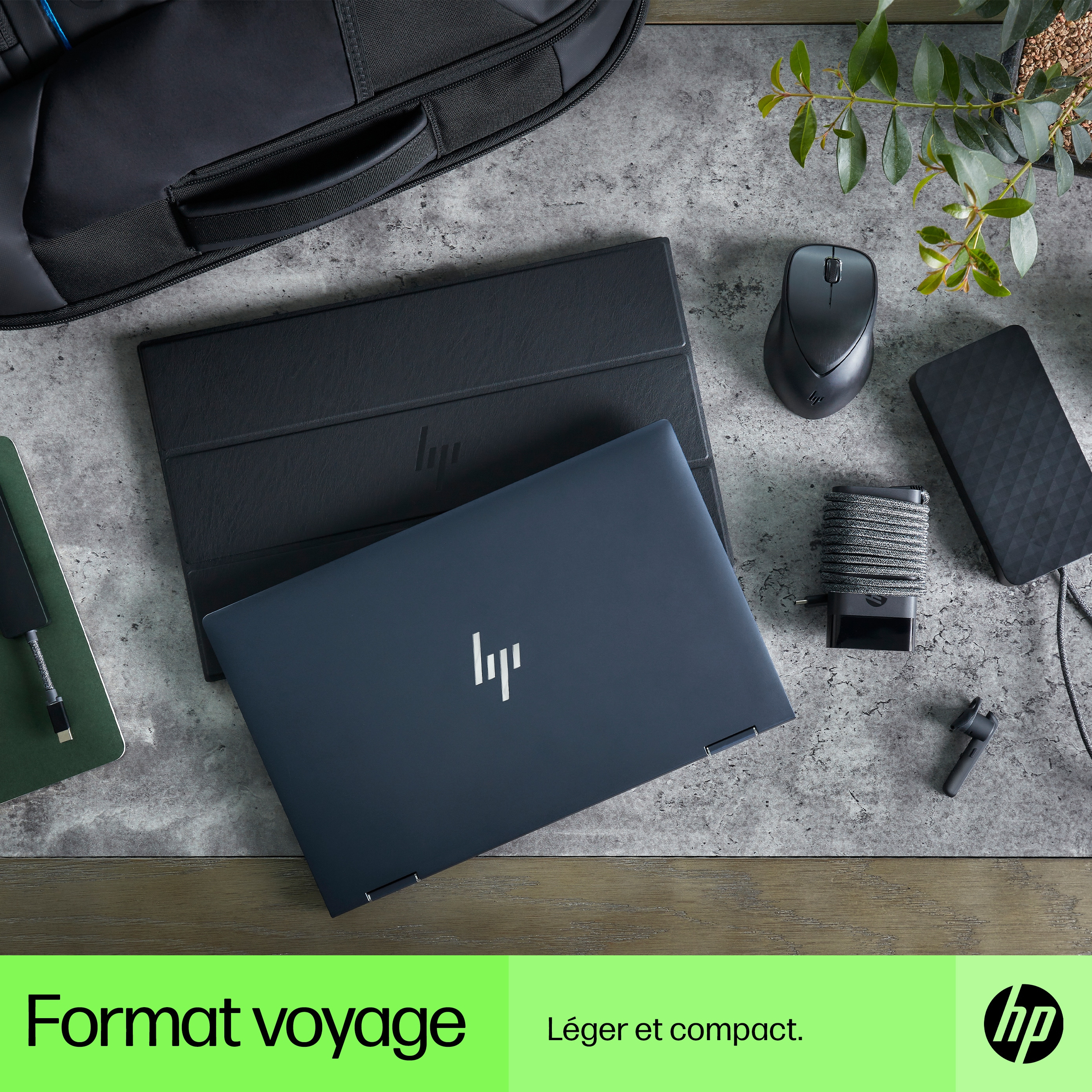 A laptop and accessories on a textured surface: a backpack, a mouse, and a hard drive.
