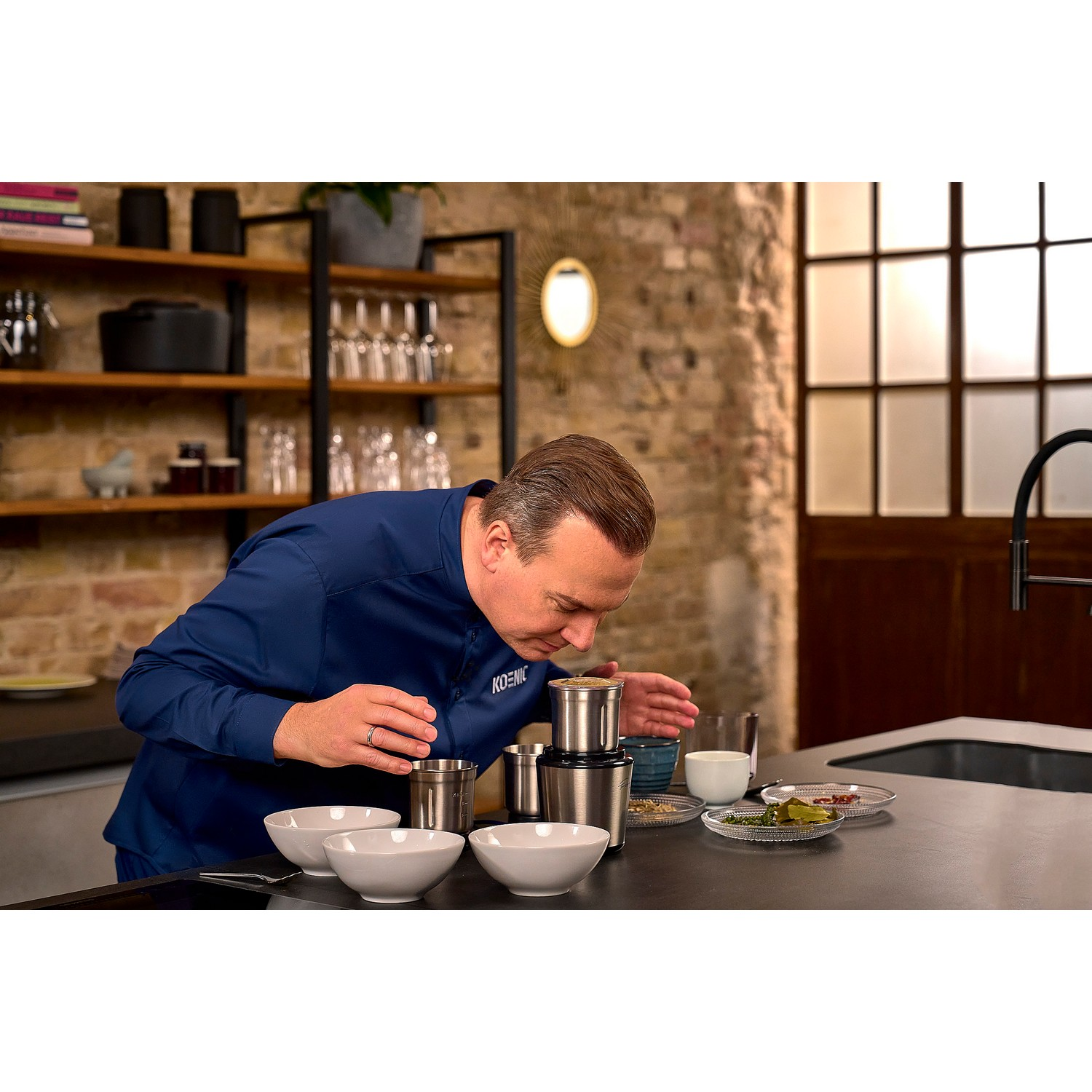 Een man die aan koffiebonen en andere ingrediënten ruikt op een aanrecht in een keuken.