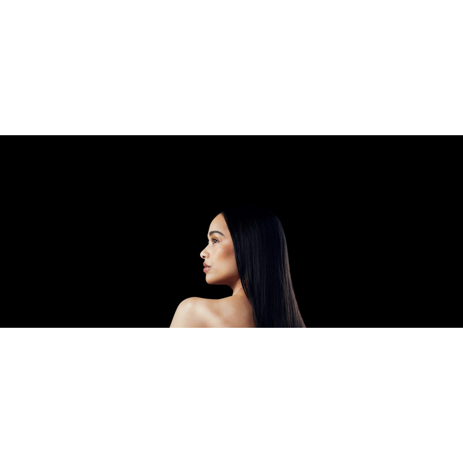 A woman with long black hair seen from the side, black background.