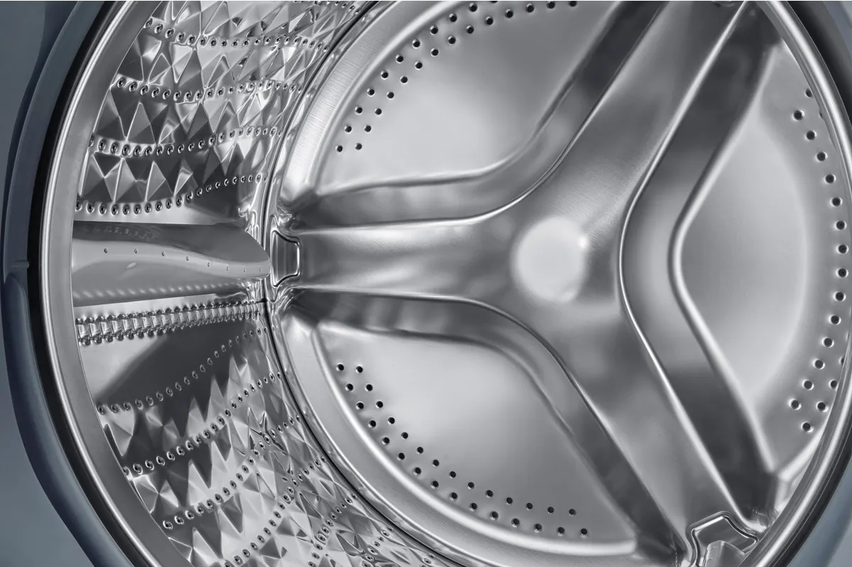 Interno di un cestello della lavatrice con superfici metalliche dettagliate. È visibile un agitatore centrale.