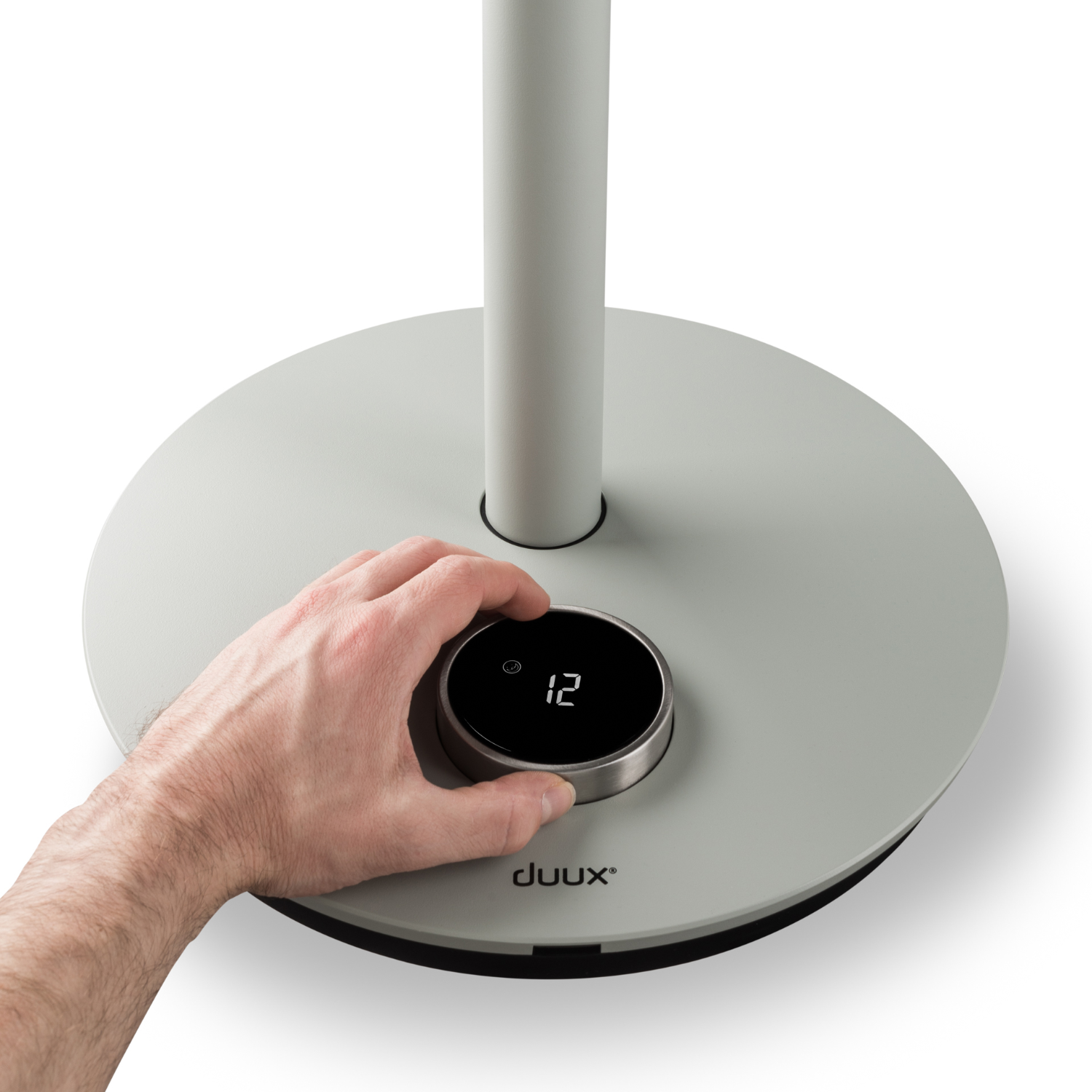 Hand draait aan de draaiknop van een grijze ventilator met '12' erop.