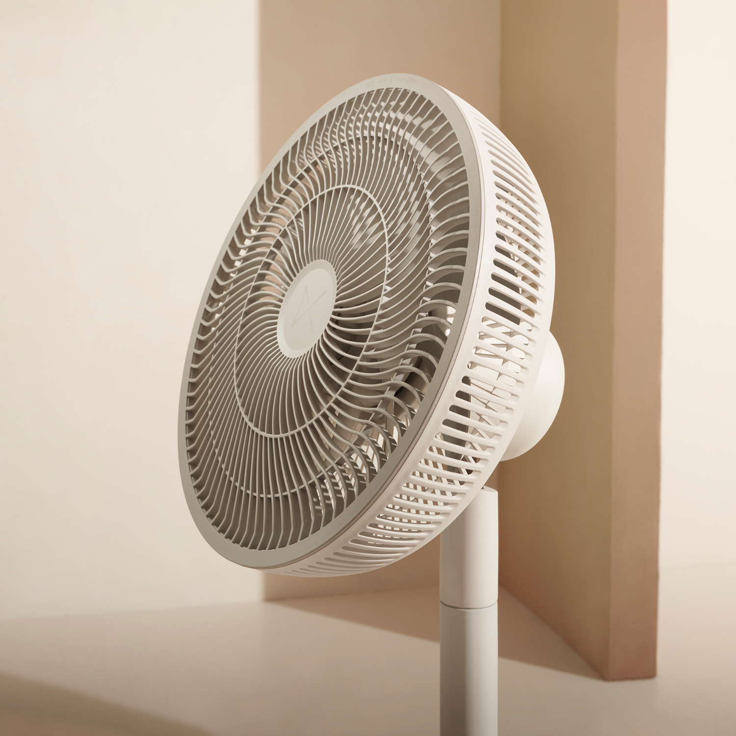 White fan with a rounded design, positioned in front of a beige backdrop.
