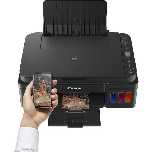 Siyah Canon yazıcı. Bir el, binanın bir görüntüsünü gösteren bir telefon tutuyor.