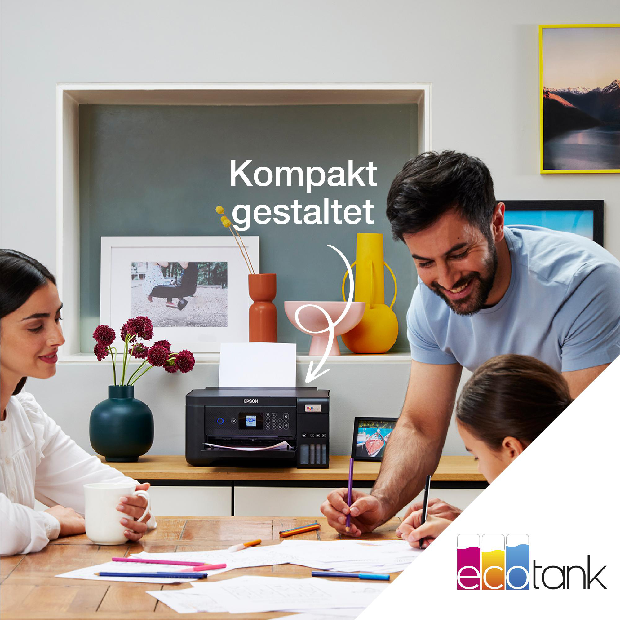 Eine Familie sitzt am Tisch. Ein Drucker steht auf dem Tisch. Text 'Kompakt gestaltet'.