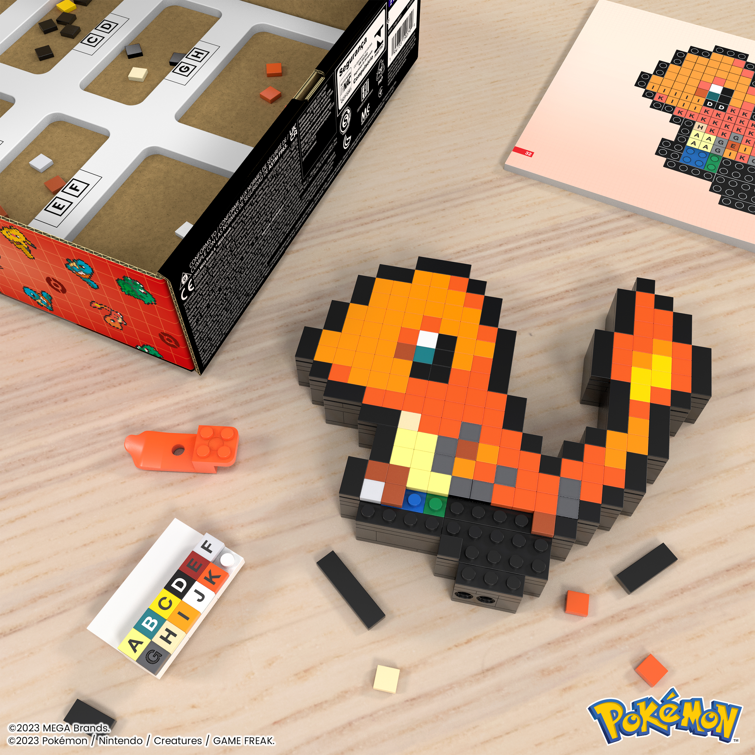 Ein Charmander LEGO-Modell mit Schachtel, Anleitung und zusätzlichen Steinen auf einem Holztisch.