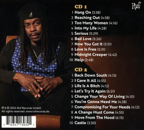 Ein Mann mit Dreadlocks trägt eine Baskenmütze und Weste. Trackliste ist sichtbar.
