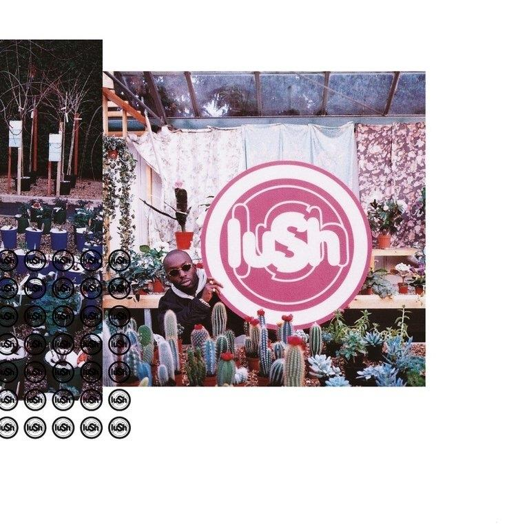 Mann mit Sonnenbrille lehnt an Schild mit "Lush". Pflanzen und Kakteen um ihn herum.