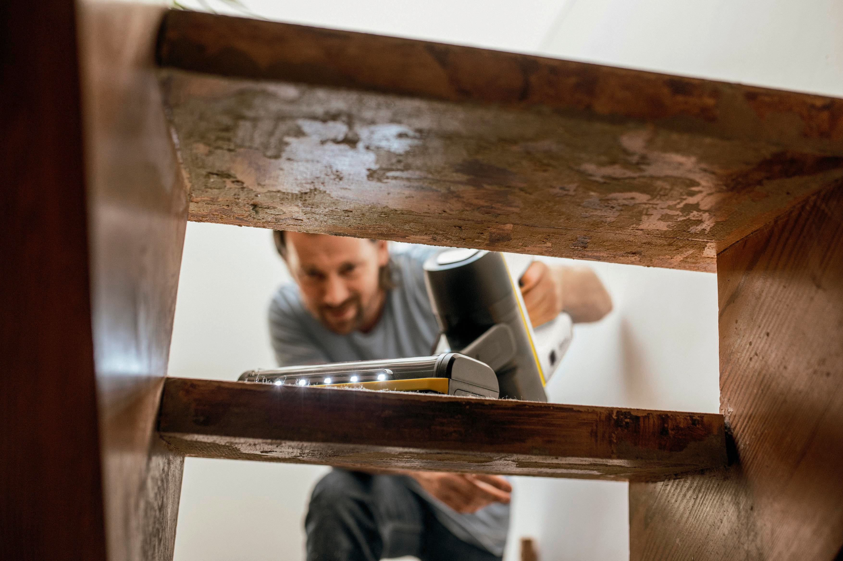 Mann reinigt Treppe mit einem Handstaubsauger.