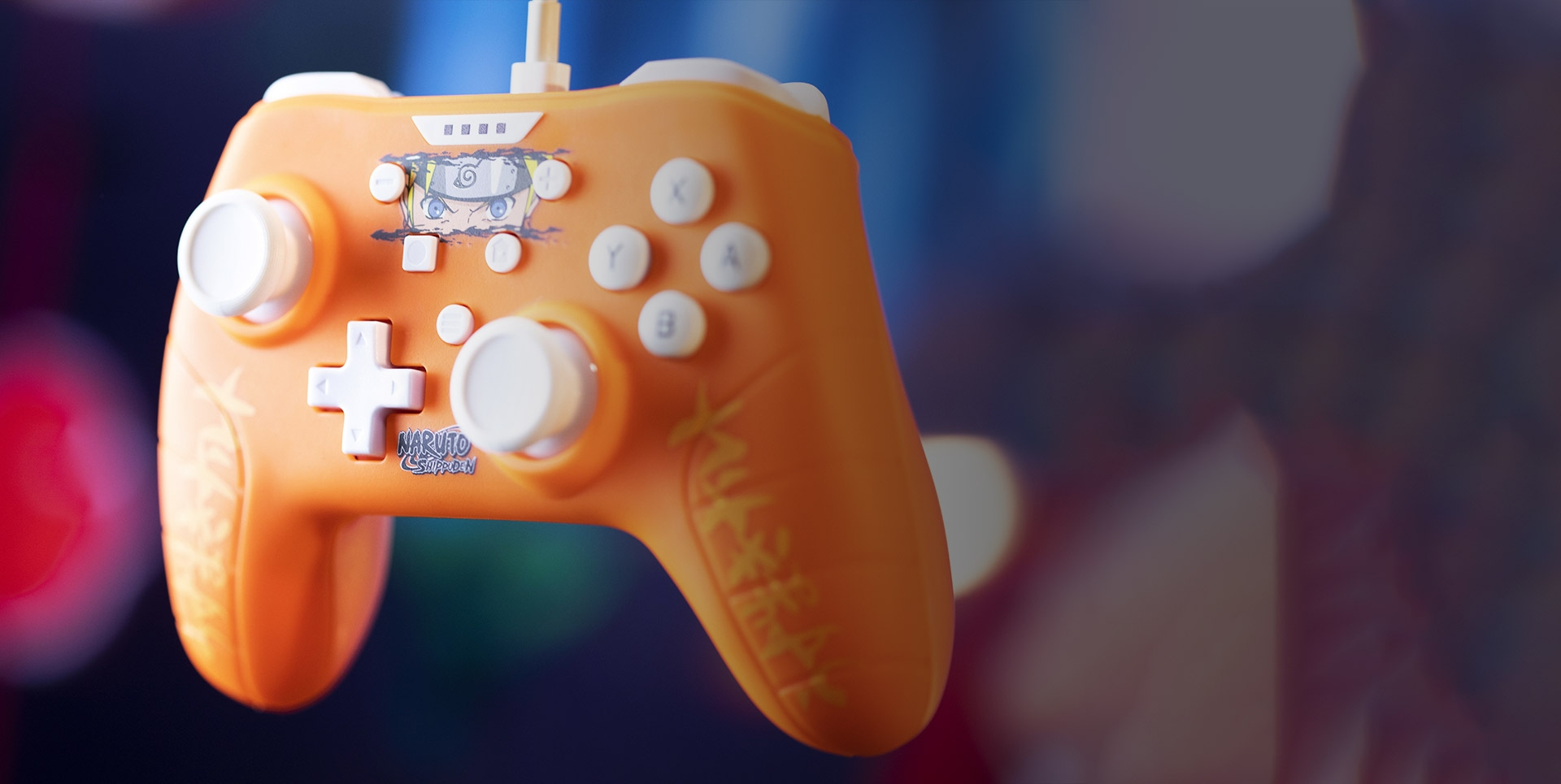 Manette de jeu orange sur le thème de Naruto avec boutons blancs, fond flou.