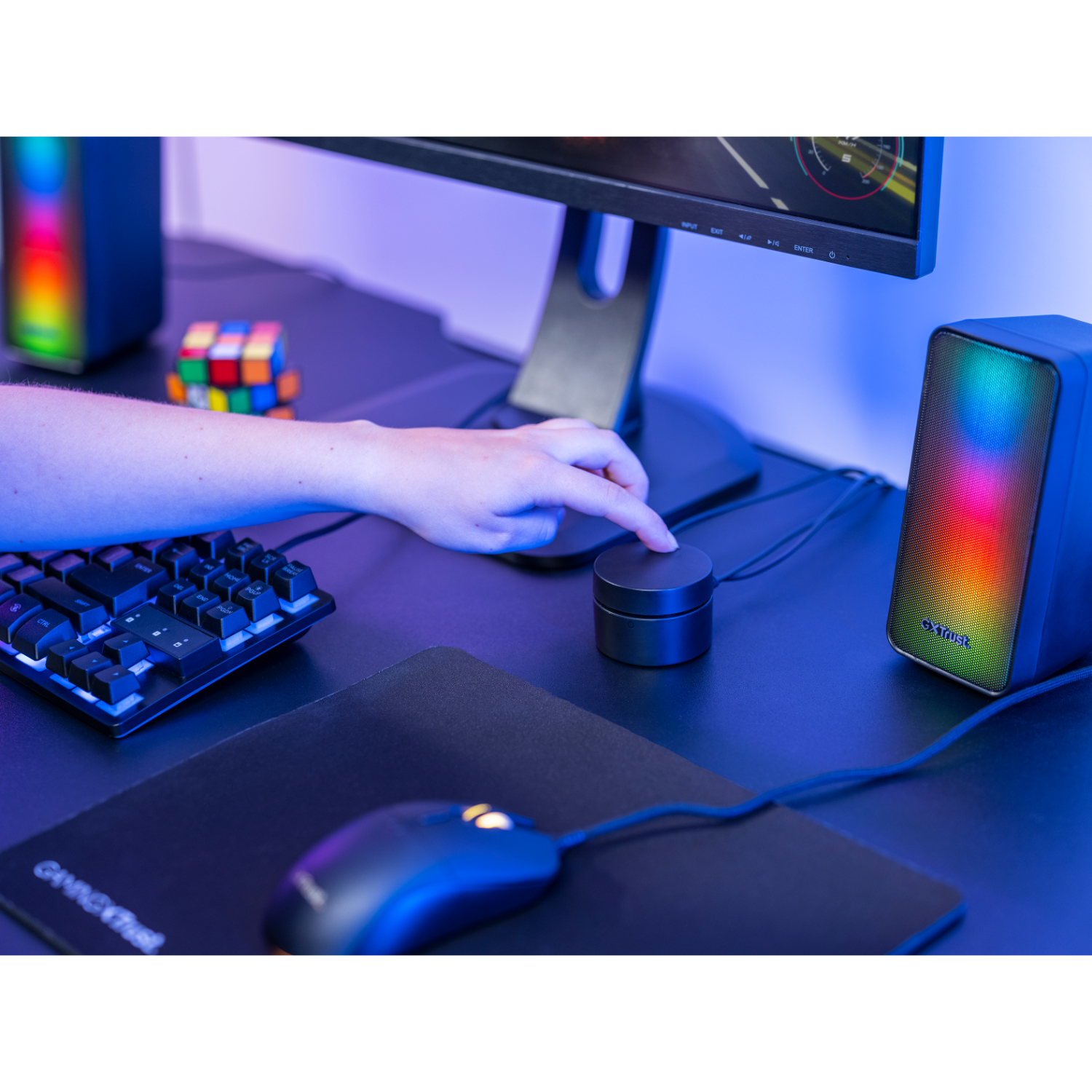 A person's hand pressing a button on a black control device next to speakers.