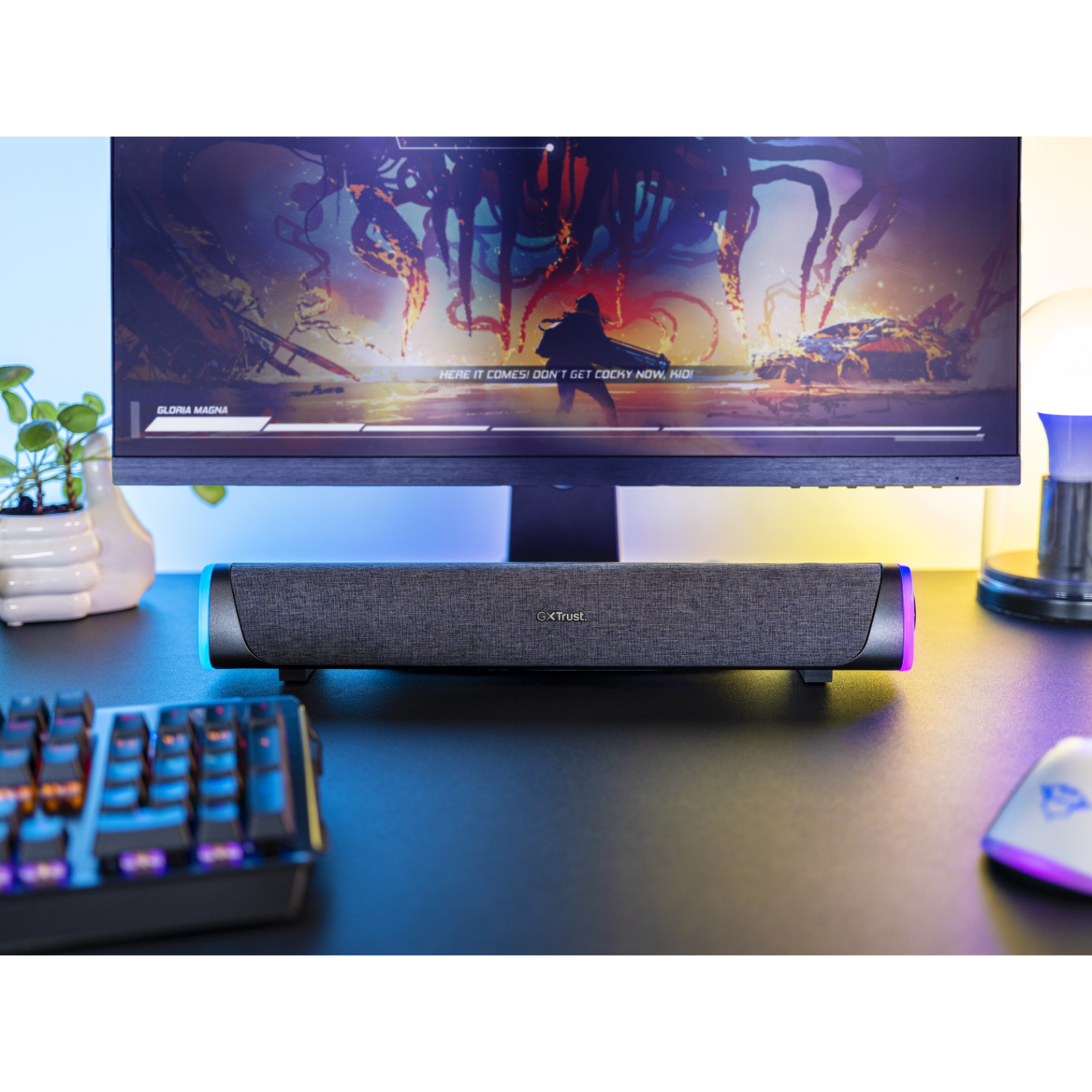 Een bureau met toetsenbord, luidspreker en monitor die een spel weergeeft.