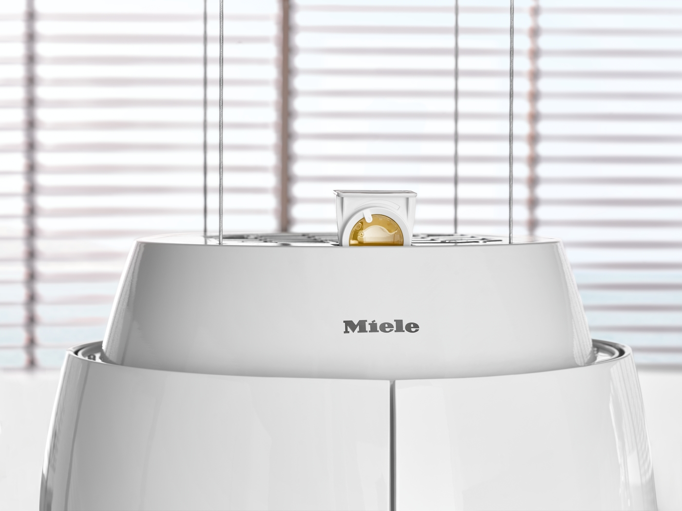 Ein weißes Miele-Gerät mit einem kleinen goldenen Behälter auf dem oberen Teil.