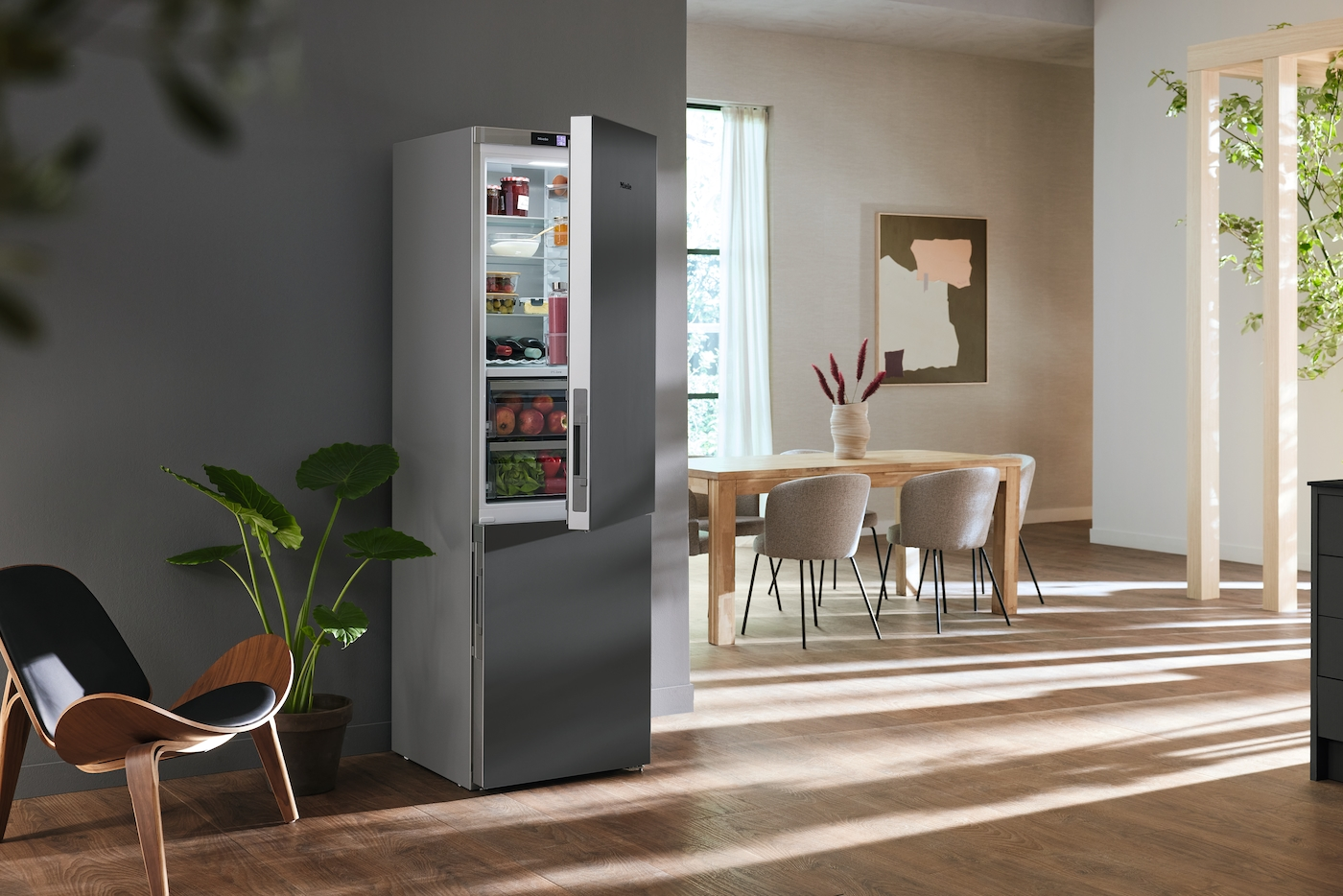 Offener Kühlschrank neben einem Sessel, Esstisch mit Stühlen im Hintergrund.