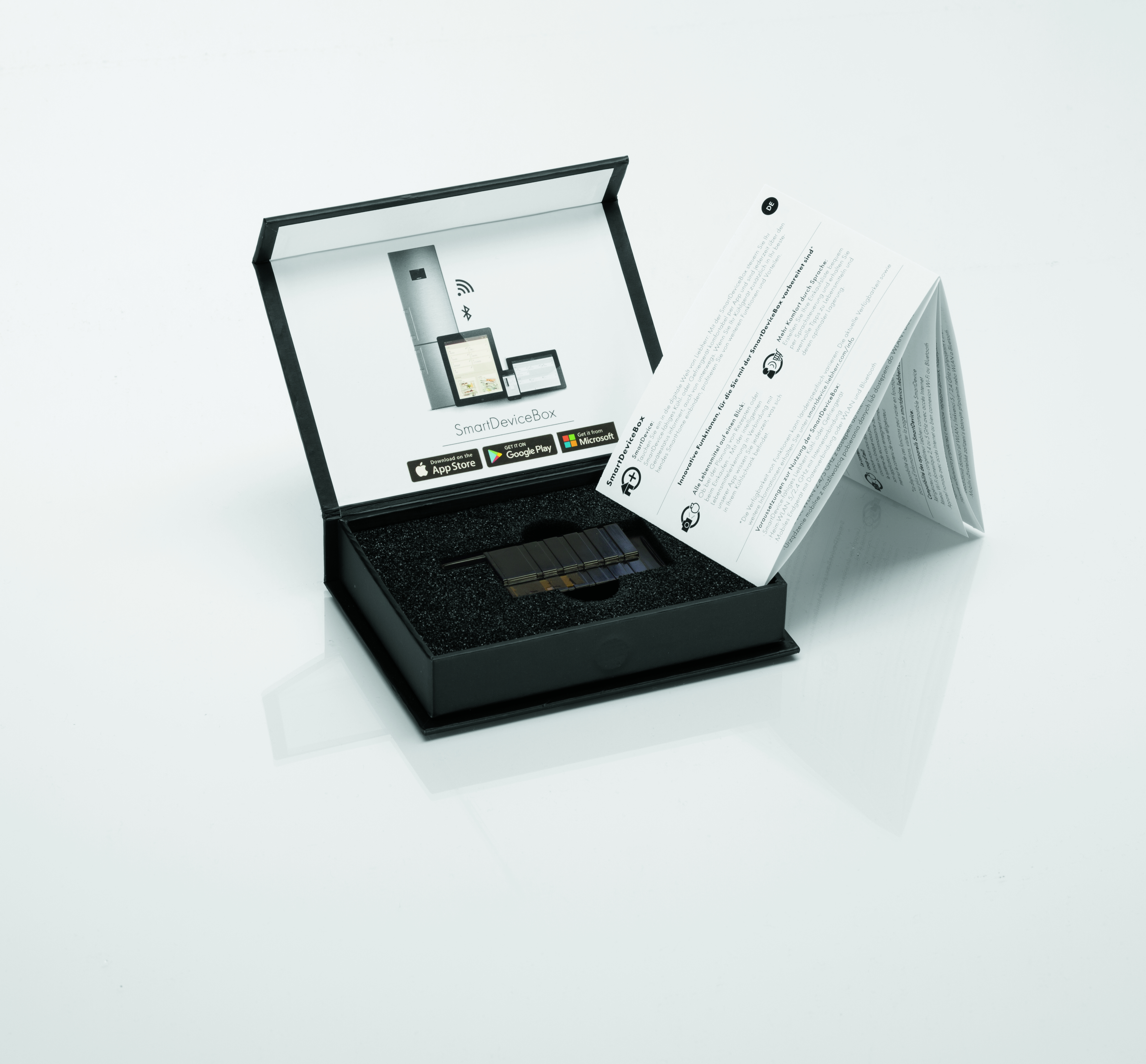 Geöffnete Box mit Gerät und Broschüre. Tablets und WLAN-Symbole werden gezeigt.
