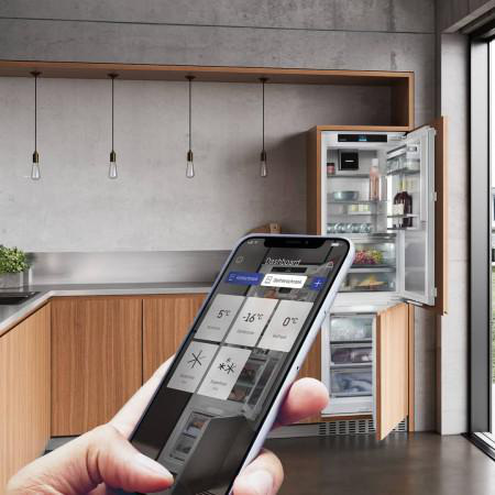 Eine Hand, die ein Telefon hält, das ein Bedienfeld für einen intelligenten Kühlschrank anzeigt.