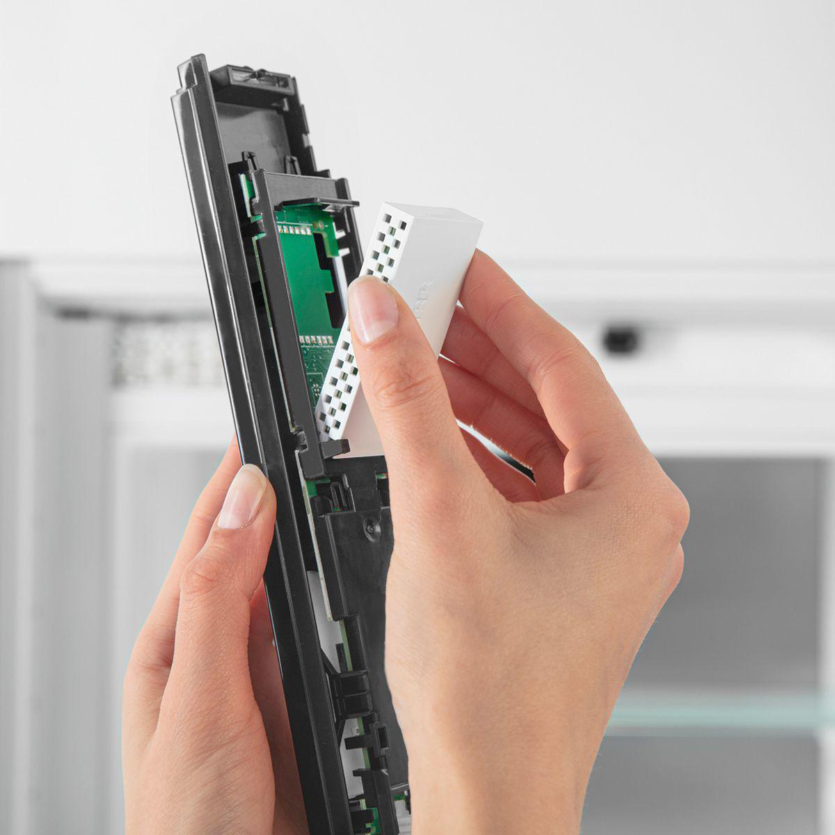 Hände, die einen weißen Filter in ein schwarzes elektronisches Gerät einsetzen, Nahaufnahme.