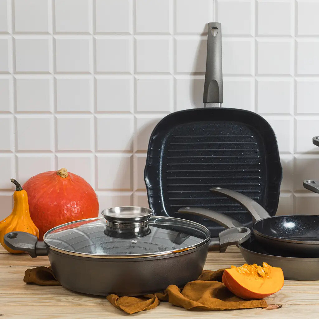 Scena kuchenna z garnkami, patelniami i dyniami na drewnianej powierzchni.