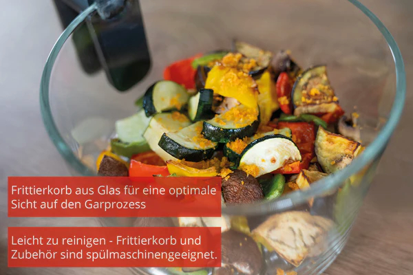 Glaschüssel mit gekochtem Gemüse. Text: 'Fritterkorb aus Glas für optimale Sicht'. Holz Hintergrund.
