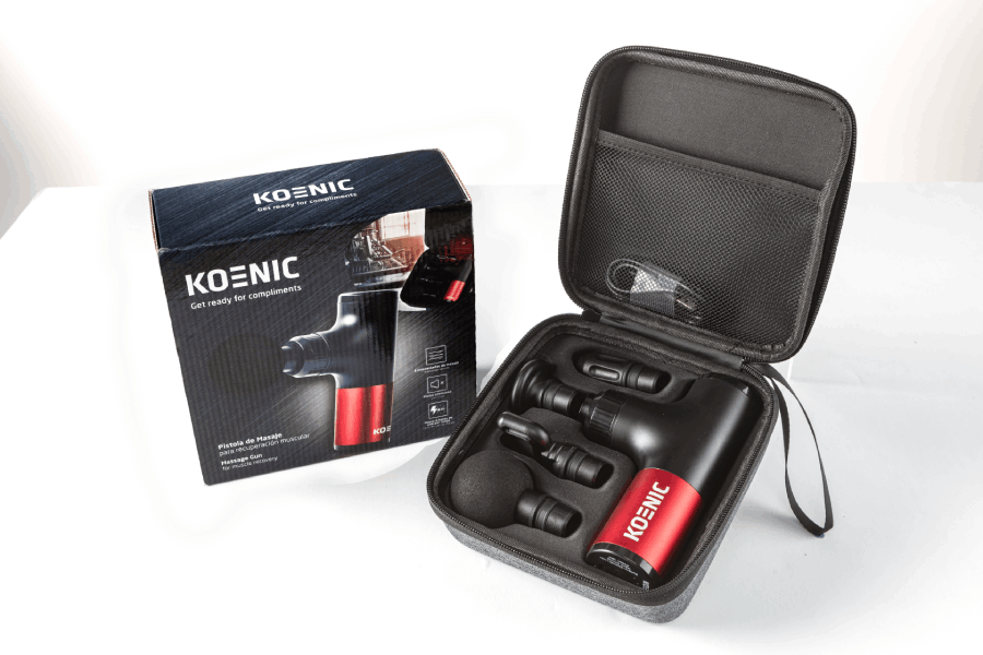 Pistola de masaje Koenic en caja y estuche abierto con cabezales.