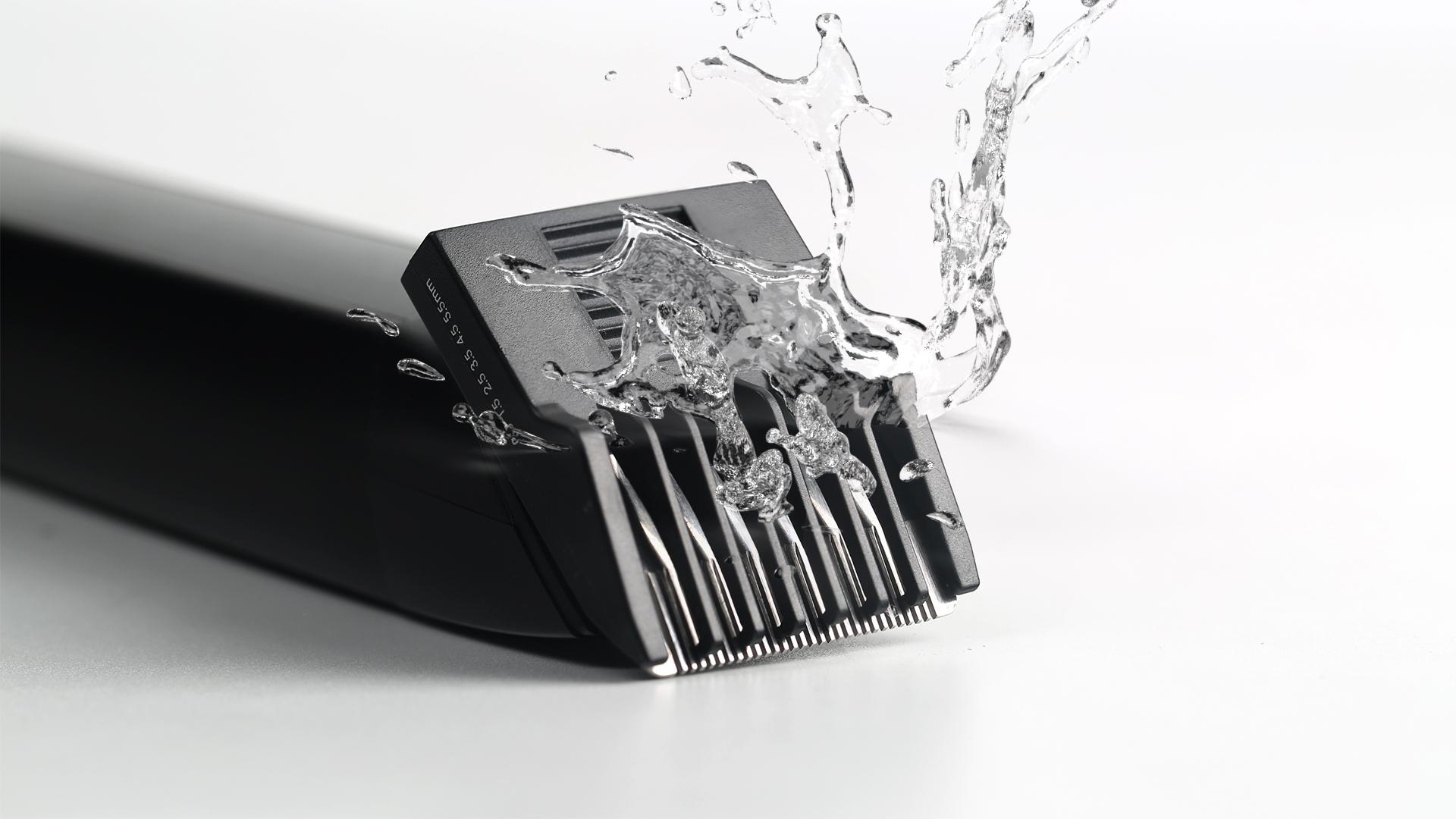 Schwarzer Haarschneider mit Wasserspritzern. Detail der Klingen und Wassersprüh.