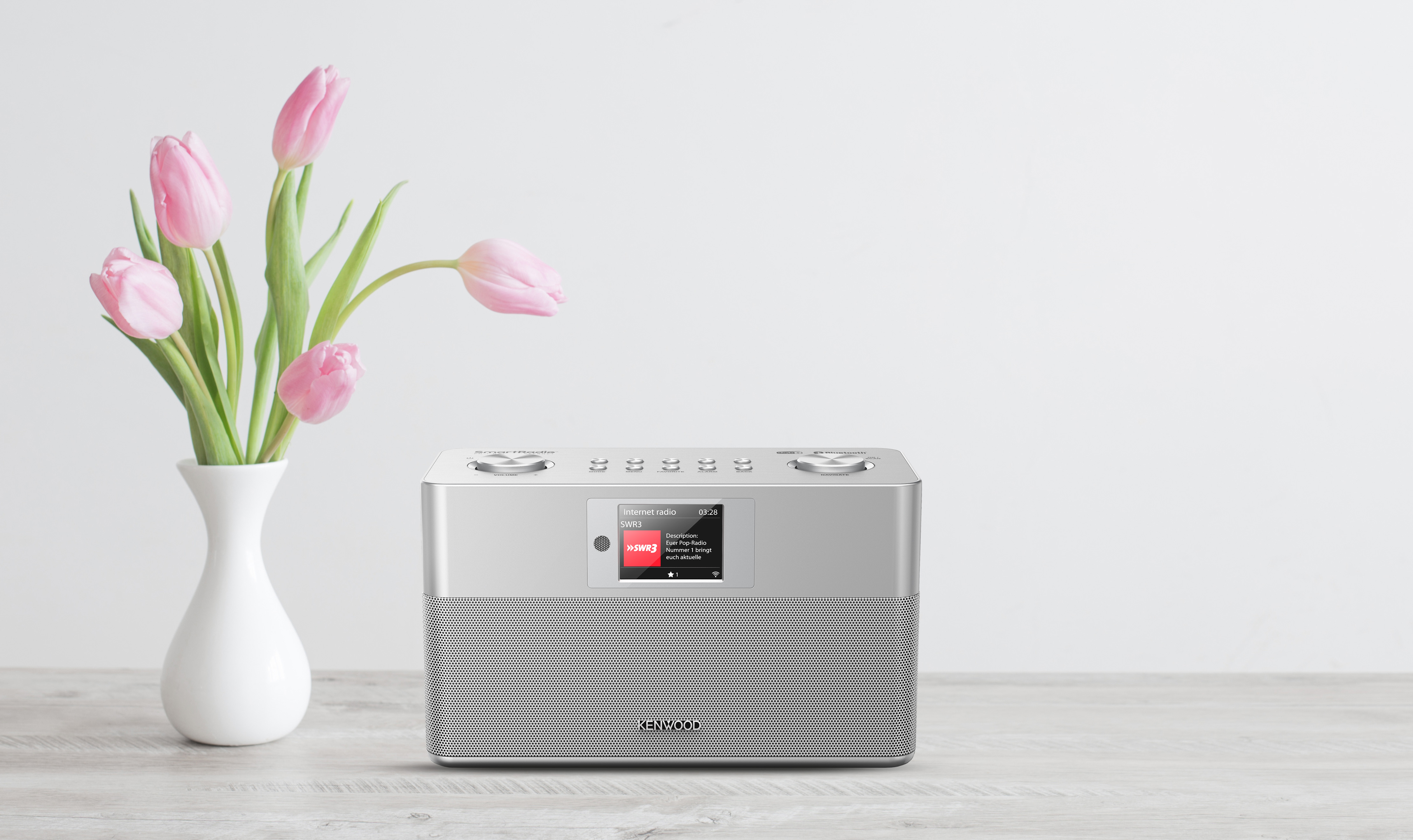Silbernes Kenwood-Radio mit einer Vase mit rosa Tulpen.