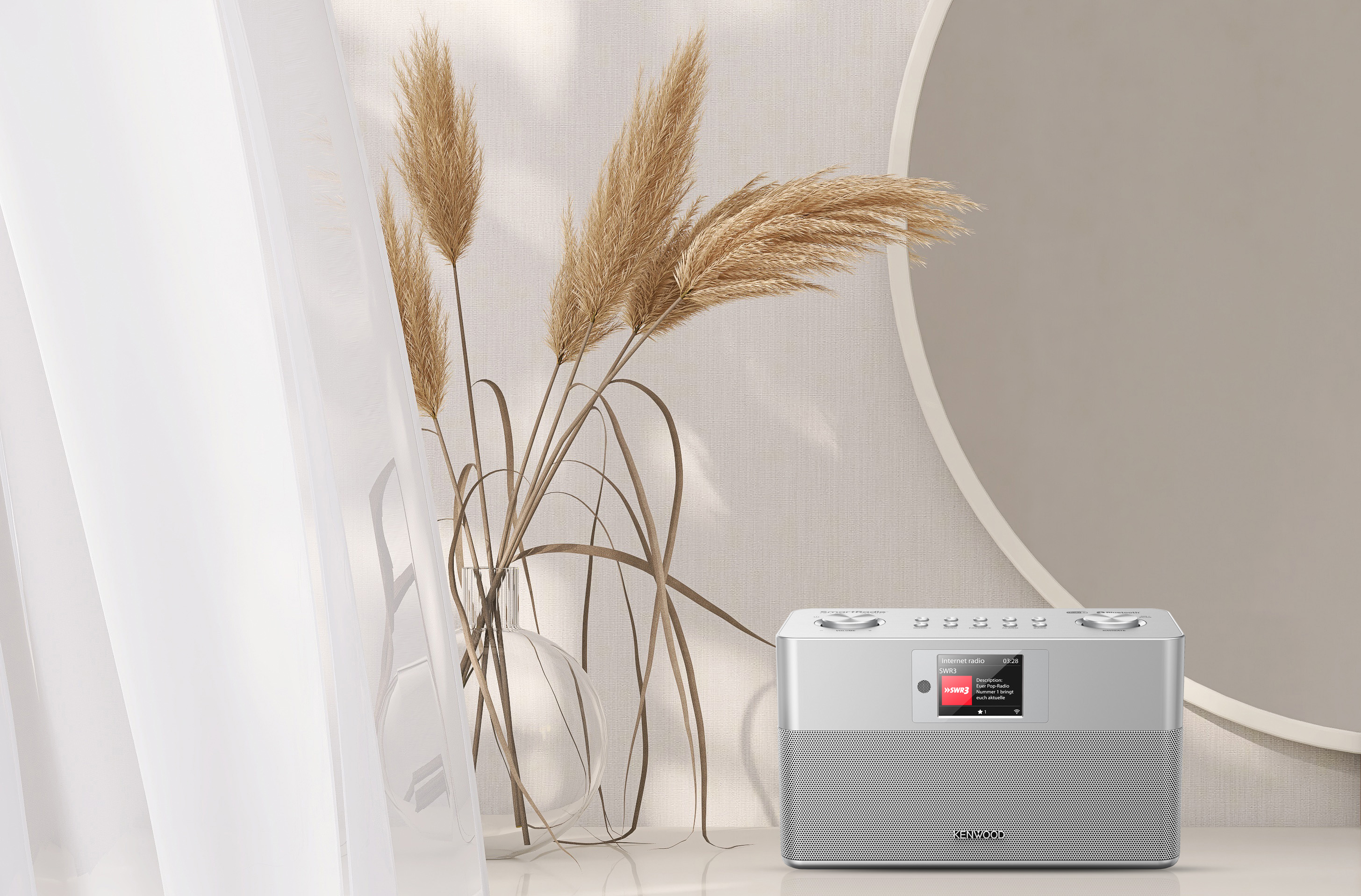Stilvolles Interieur mit Radio auf dem Tisch, Pampasgras in einer Vase und rundem Spiegel.