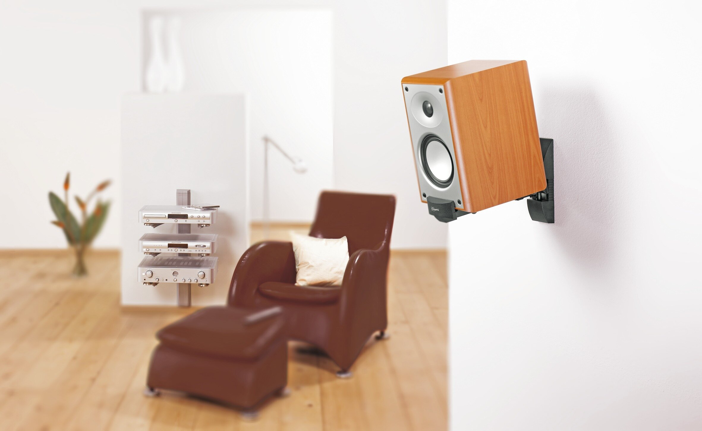 Drewniany głośnik zamontowany na białej ścianie w salonie, z krzesłem i dekoracją.