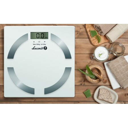 Biała waga cyfrowa z drewnianym tłem. Zawiera aloes i inne przedmioty.