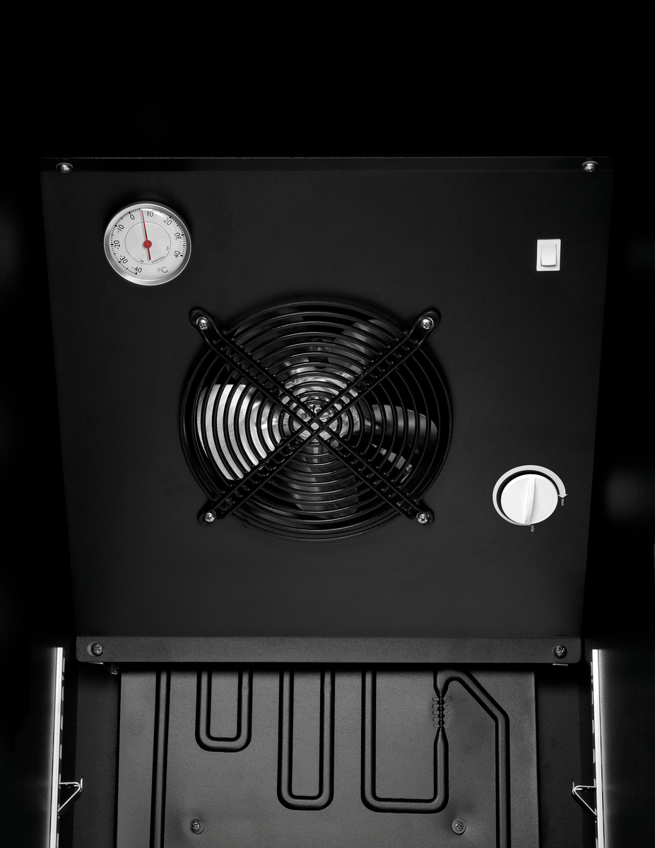 Nahaufnahme eines schwarzen Geräteinneren. Es zeigt einen Ventilator, ein Thermometer, Bedienelemente und ein Kühlsystem mit schwarzem Hintergrund.