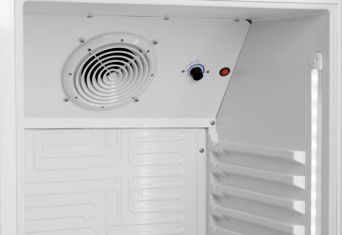 Innerhalb eines weißen Kühlschranks. Ein Ventilator, ein Bedienknopf und ein roter Knopf sind sichtbar. Das Innere hat ein strukturiertes Muster.