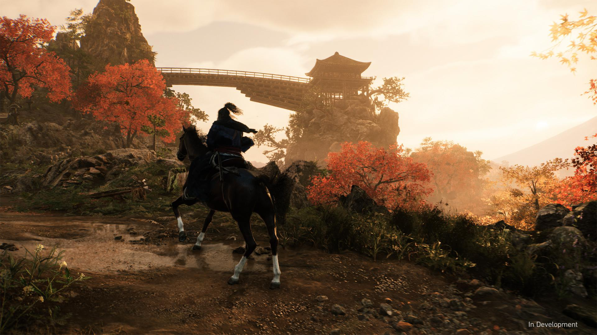 Ein Reiter auf einem schwarzen Pferd, in einer Landschaft mit Bergen, einer Brücke und Herbstbäumen.