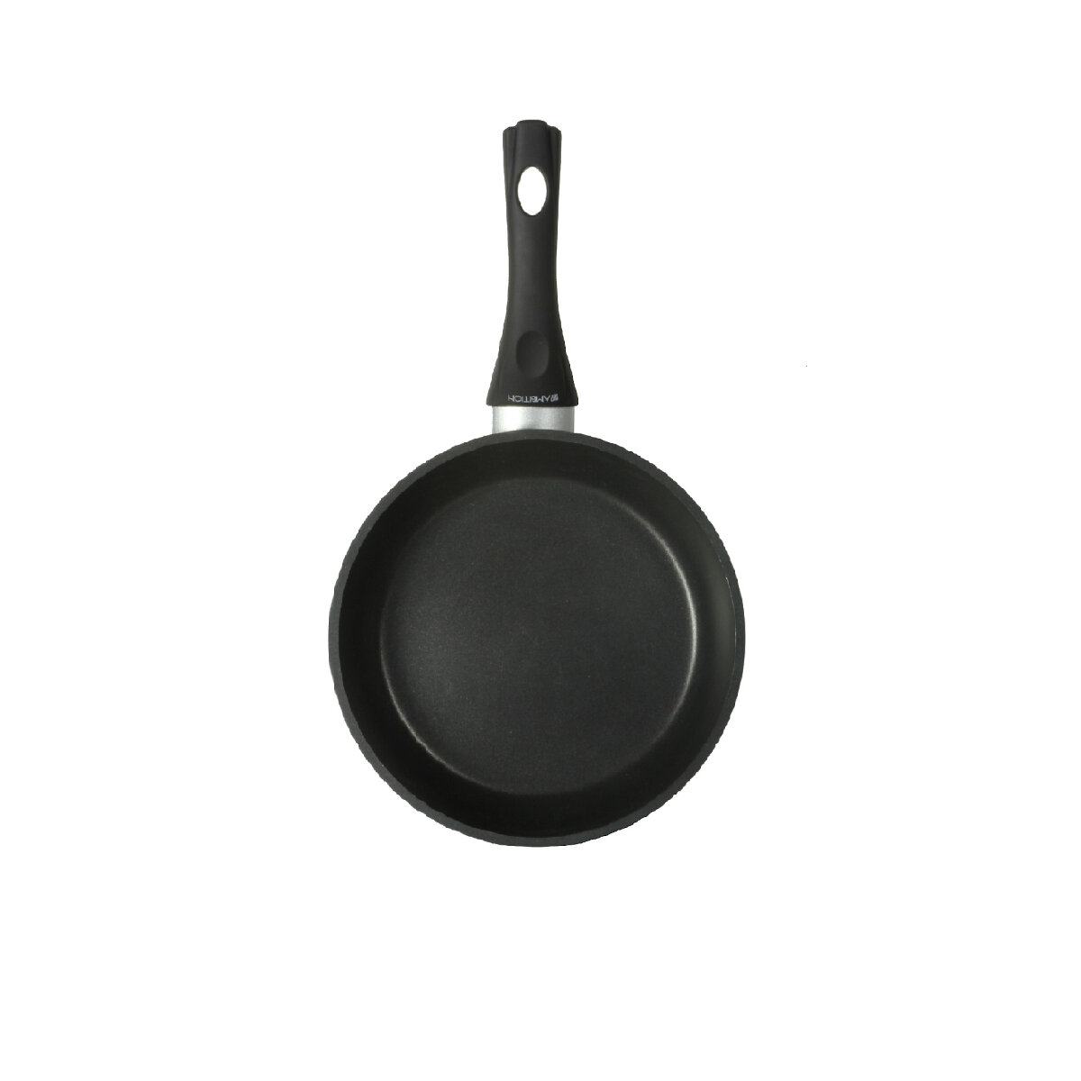 Czarna patelnia z uchwytem na białej powierzchni, z białym tłem. Widok z góry.