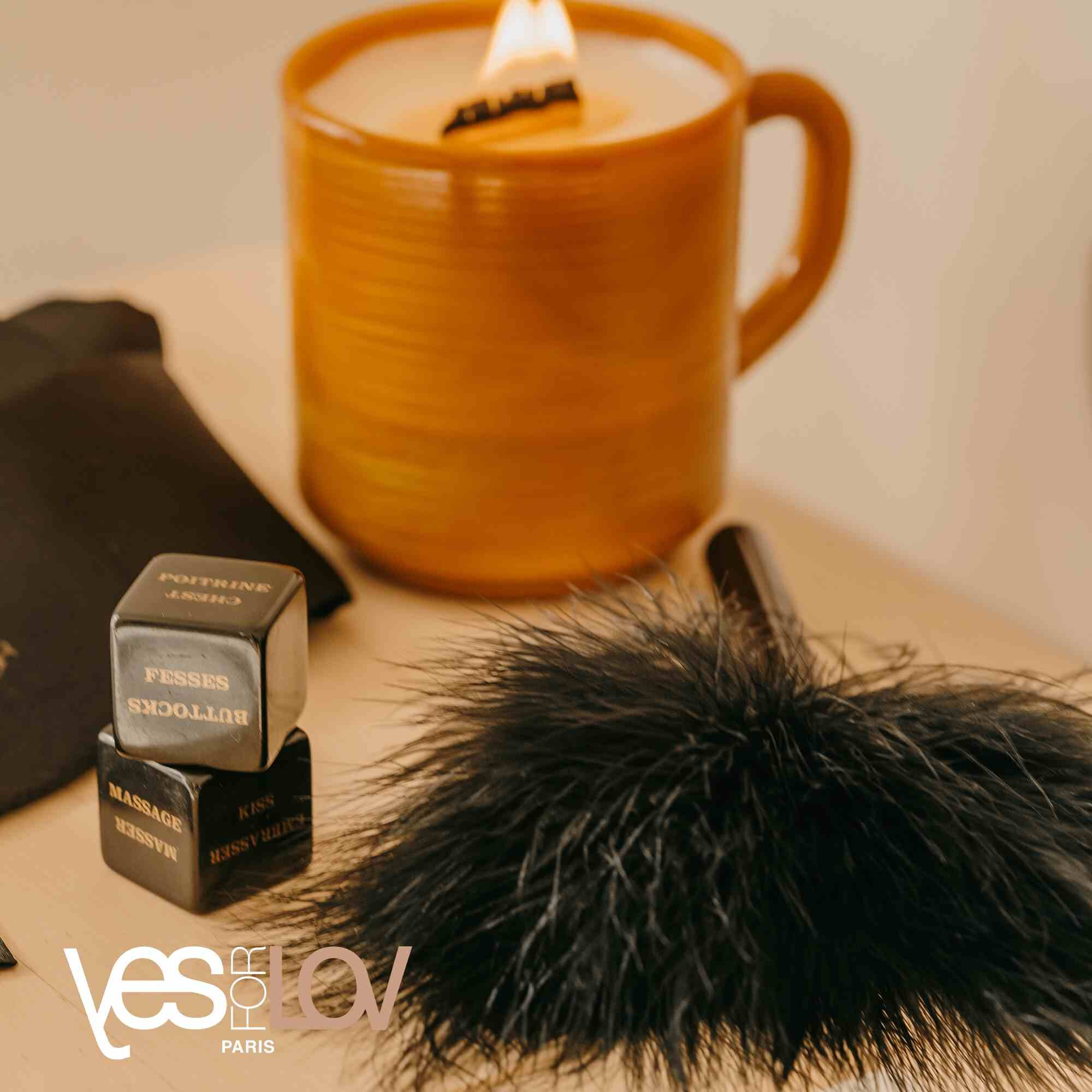 Świeca w kubku, kostki z tekstem i pióropusz. Beżowa powierzchnia.