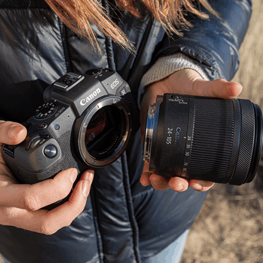 Persona sosteniendo una cámara Canon EOS R y un lente 24-105mm, al aire libre, fondo borroso.