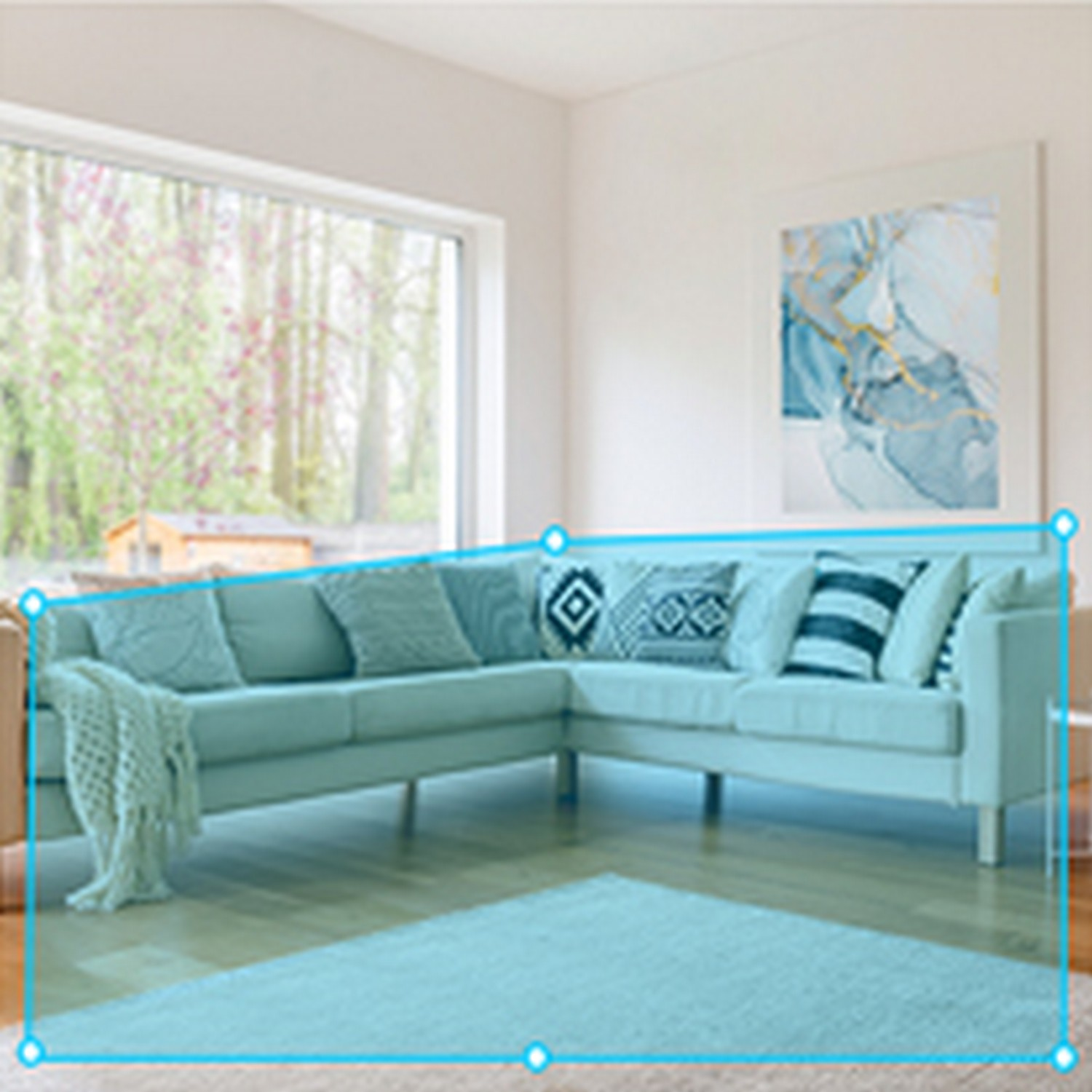 Un canapé sectionnel bleu clair, avec des coussins et une couverture, dans un salon avec une fenêtre et une peinture.