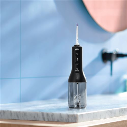 Black water flosser on a white countertop. It has a water reservoir and various buttons.
