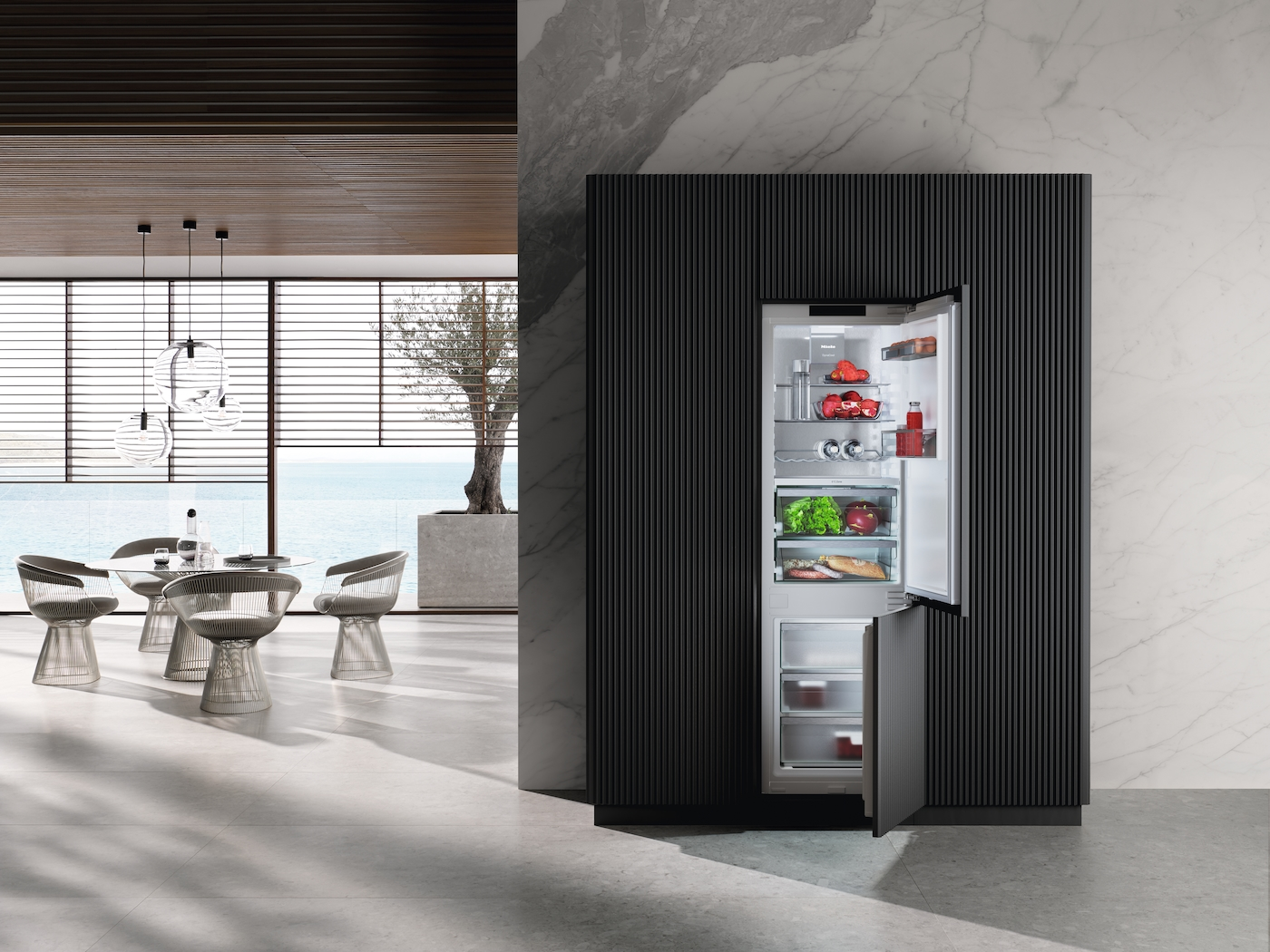 Ein moderner Essbereich mit Blick auf das Meer und ein offener Kühlschrank.