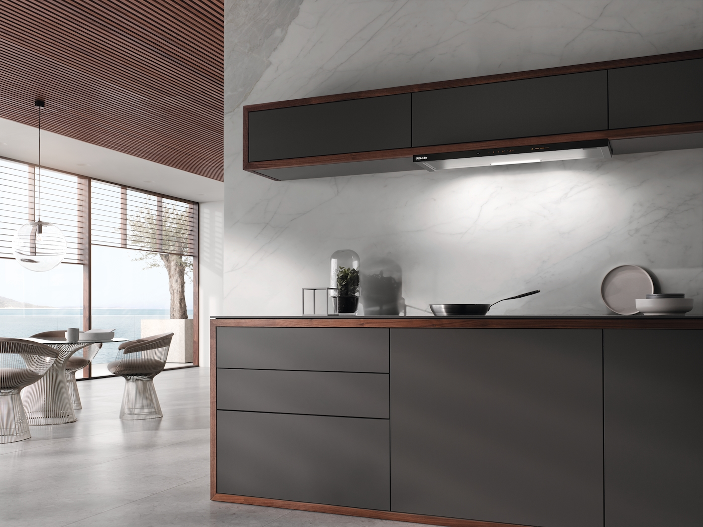 Moderne Küche mit Marmorrückwand, dunklen Schränken und Blick auf das Meer.