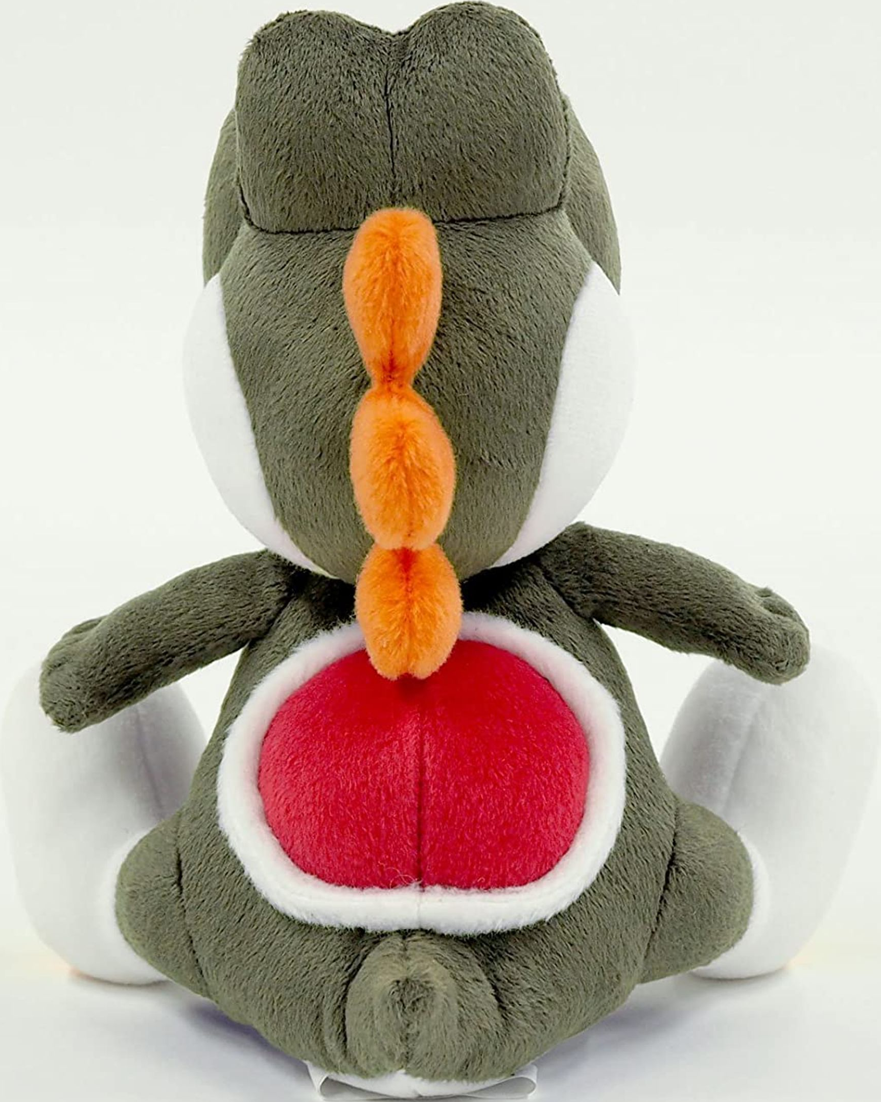 Retro di un peluche di Yoshi, corpo verde, guscio rosso, spine arancioni.
