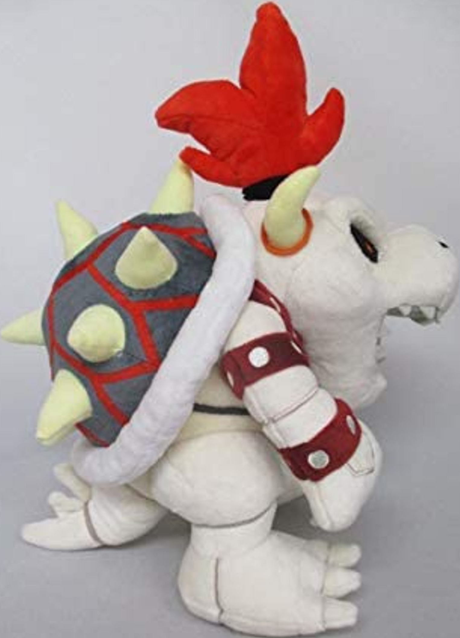 Peluche Bowser, une créature blanche et grise ressemblant à un dragon avec des pointes rouges et une carapace rouge.