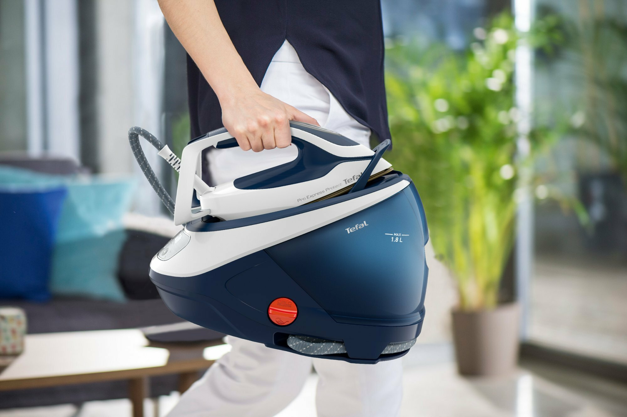 Osoba trzymająca niebiesko-białe żelazko parowe z uchwytem i zbiornikiem na wodę.