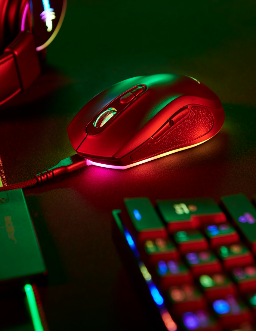 Piros-fekete gamer egér RGB-világítással és egy billentyűzettel a háttérben.