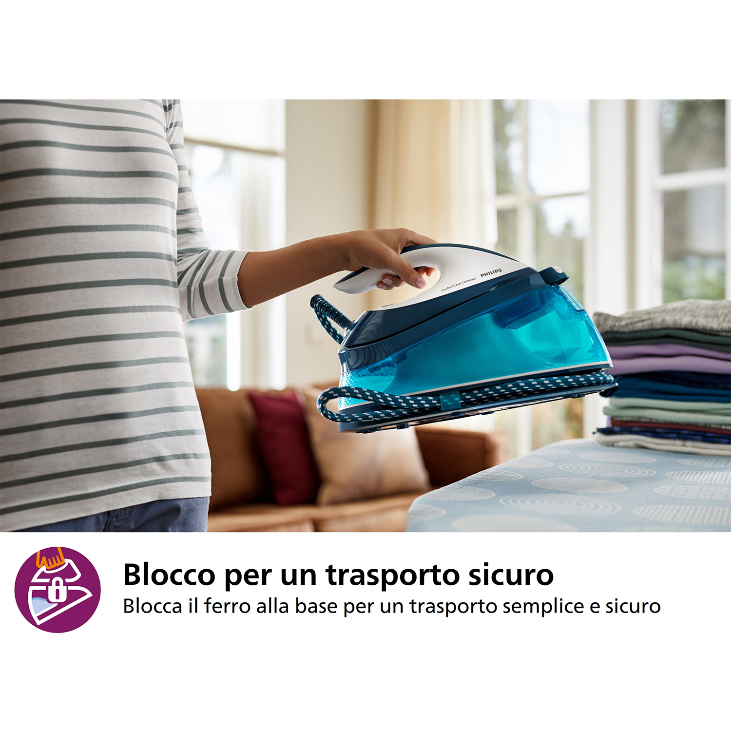 Una persona che tiene un ferro da stiro blu e bianco. Una pila di vestiti a destra.