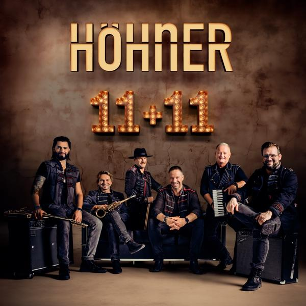 Band Höhner, Gruppenfoto. Mitglieder in Schwarz, vor beleuchteten Buchstaben stehend.