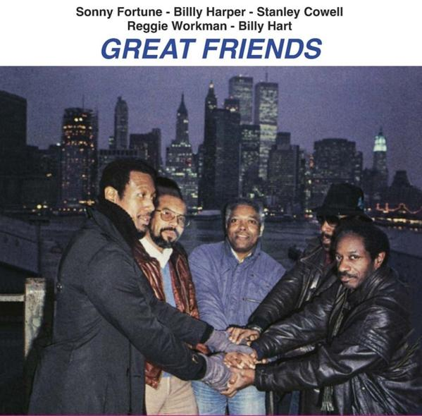 Öt férfi kabátban és dzsekiben, összefogva a kezük, egy városkép előtt. Az album címe: Great Friends.