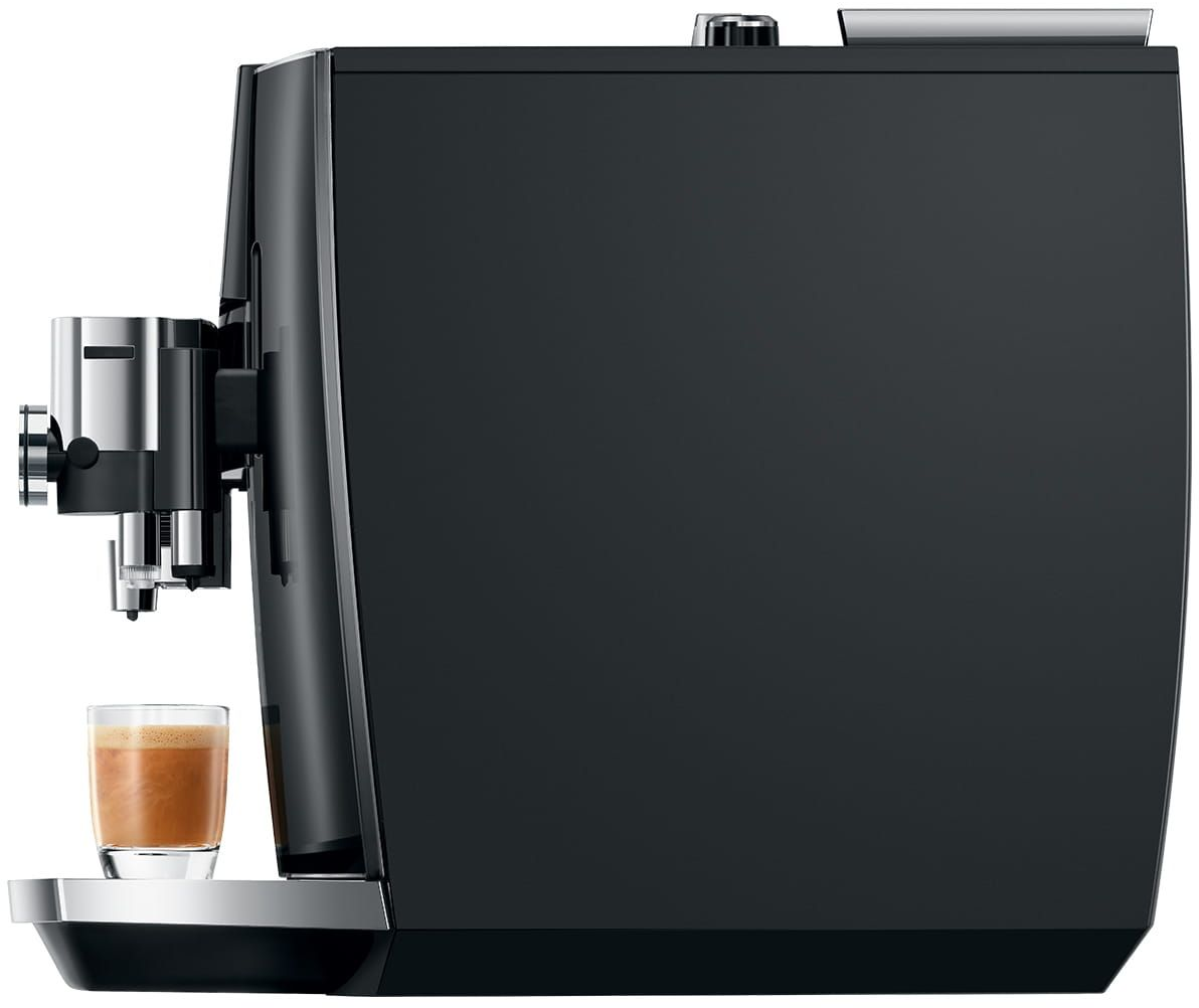 Schwarze Espressomaschine mit einem Glas Kaffee. Seitenansicht. Silberne Details. Schwarzer Hintergrund.
