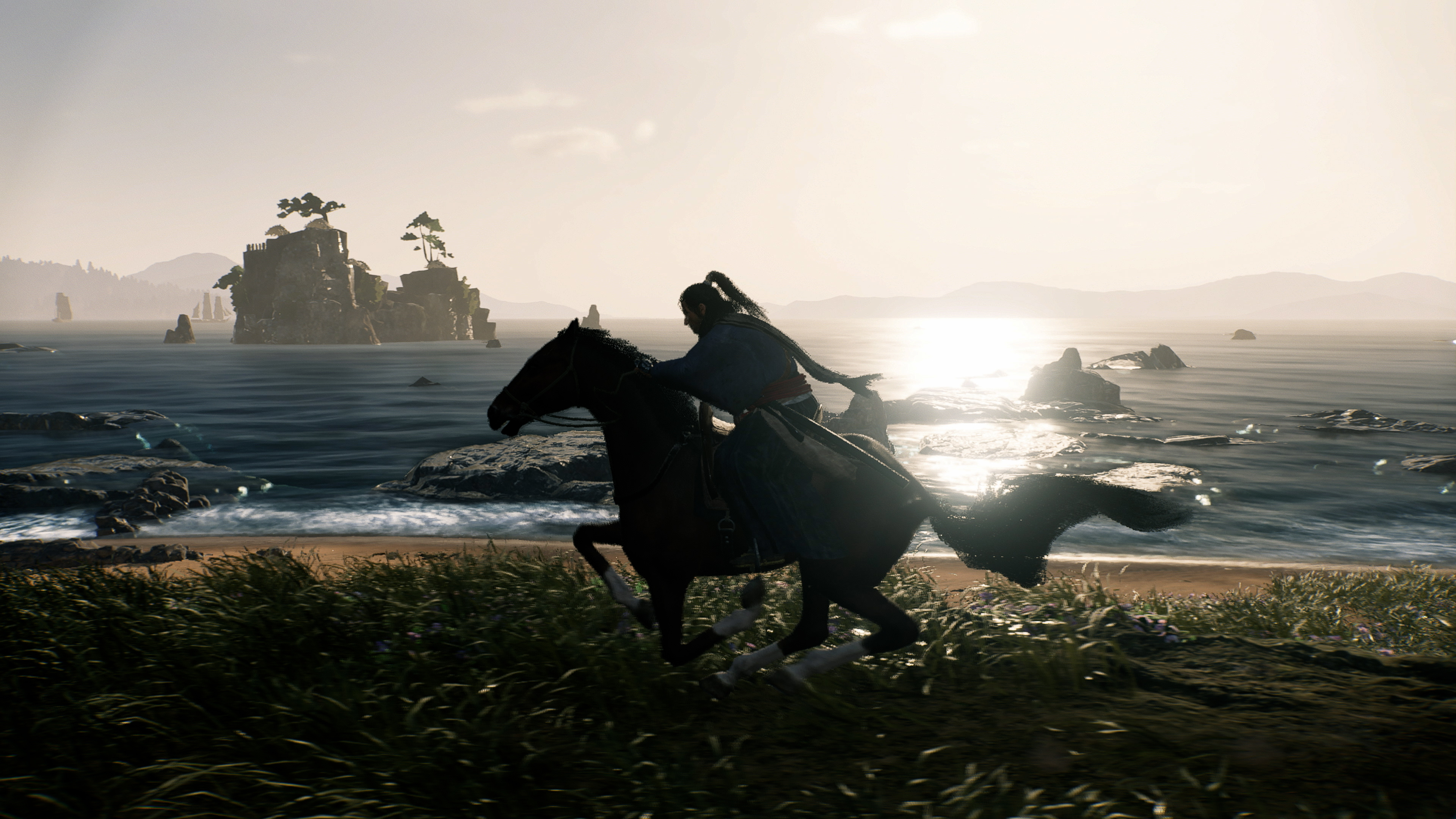 Een persoon te paard op het strand, met water en een rotsachtig eiland op de achtergrond.