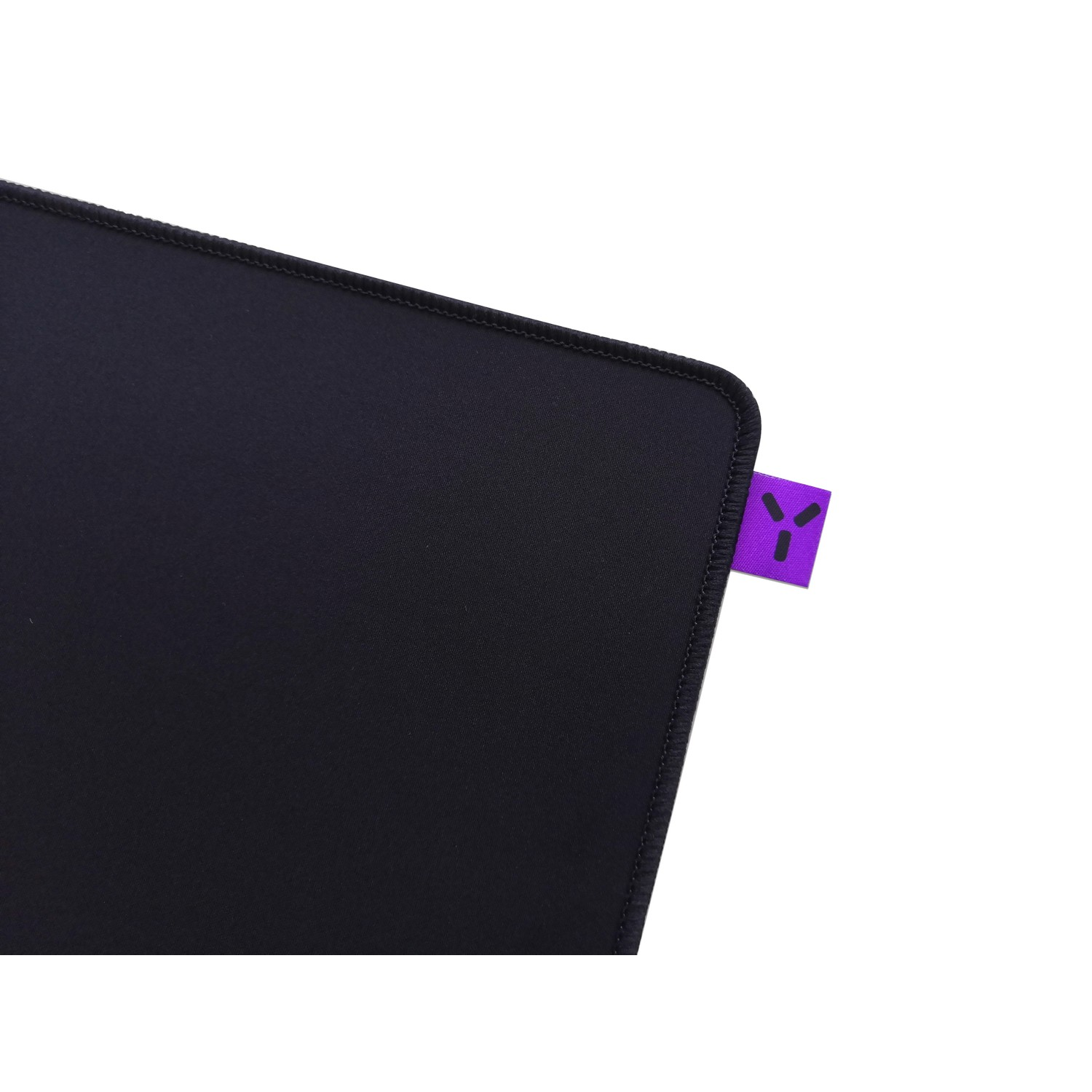 Black mousepad with a purple logo tag, close-up of the corner.