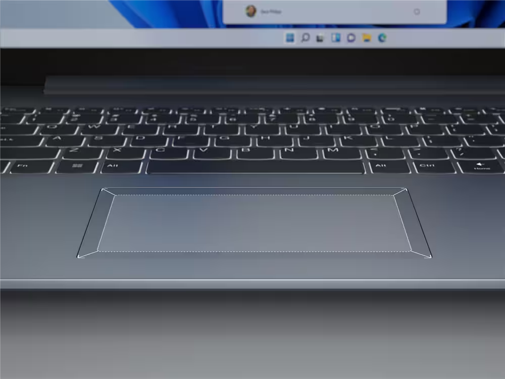 Nahaufnahme einer Laptop-Tastatur und eines Touchpads. Der Bildschirm zeigt eine Suchleiste. Die Tastatur ist hintergrundbeleuchtet.